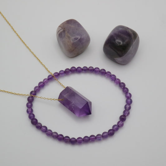 Amethyst Crystal on a fine gold chain surrounded by a Amethyst crystal bracelet and two Amethyst tumblestone crystals