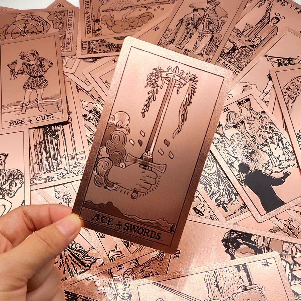 A rose gold tarot card held up showing its design on the front