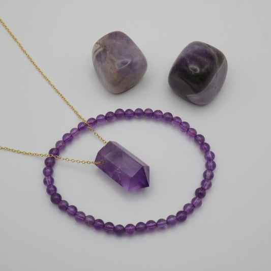 Amethyst Crystal on a fine gold chain surrounded by a Amethyst crystal bracelet and two Amethyst tumblestone crystals 