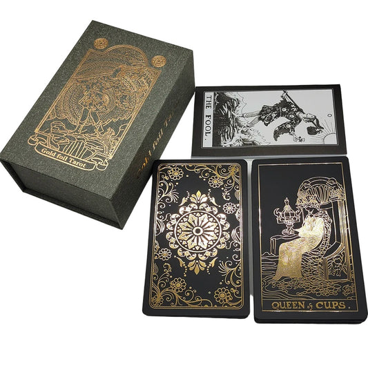 Tarot card deck, showing flowers in gold on a black background on the back face of a card alongside a case and tarot meaning booklet